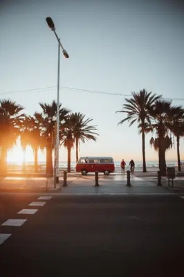 a red car parked in a parking lot with palm trees at Retro VW Kombi T2 Campervan in Hospitalet de Llobregat