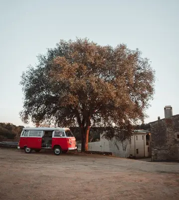 a red van parked in front of a tree at Retro VW Kombi T2 Campervan in Hospitalet de Llobregat