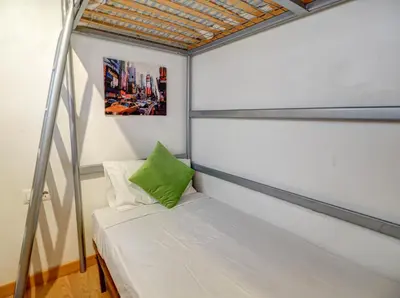 a bed in a small room with a green pillow at Carmen Apartment by Hello Homes Sitges in Sitges