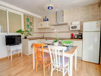 a kitchen with a table and chairs and a white refrigerator at Carmen Apartment by Hello Homes Sitges in Sitges