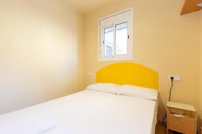a bedroom with a bed with a yellow headboard and a window at Apartment Bed&BCN Sant Andreu II in Barcelona
