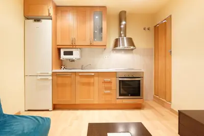 a kitchen with wooden cabinets and a refrigerator at Apartment Bed&BCN Sant Andreu II in Barcelona