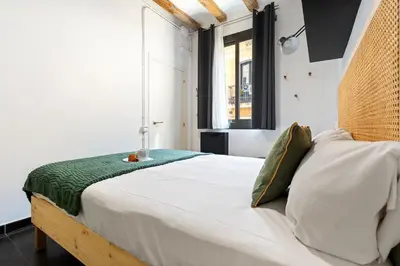 a bedroom with a bed with white sheets and a window at Lodging Apartments Almirall Beach 22 in Barcelona