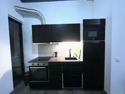 a black kitchen with a sink and a refrigerator at Studio Sagrada Familia in Barcelona
