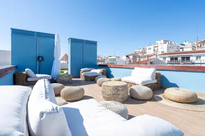 a patio with white furniture and a swimming pool at Hauzify I Apartaments Voramar in San Pol de Mar