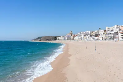a sandy beach with buildings in the background at Hauzify I Apartaments Voramar in San Pol de Mar