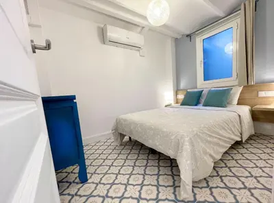 a bedroom with a bed with blue pillows and a window at Lazy Donkey Sagrada Familia in Barcelona