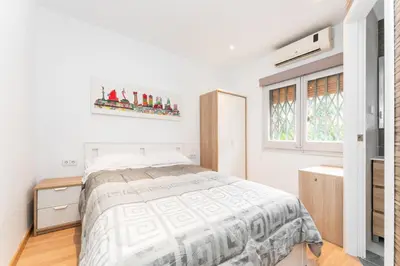 a white bedroom with a bed and a window at La Sagrera House in Barcelona