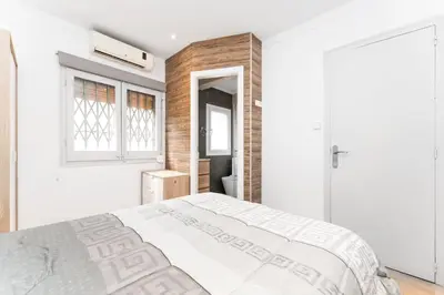 a white bedroom with a bed and a window at La Sagrera House in Barcelona