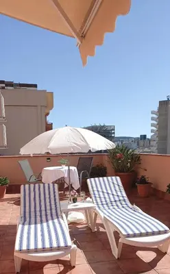 two lounge chairs and an umbrella on a patio at Cozy and sunny penthouse Fira BCN in Hospitalet de Llobregat
