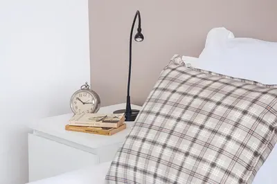 a bedside table with a clock and a book at Durlet Rambla Mar Apartments in Barcelona