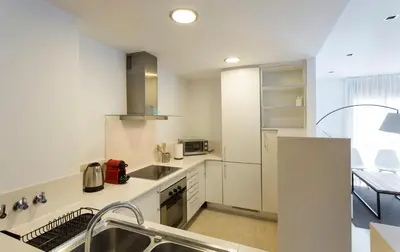 a white kitchen with a sink and a stove at Durlet Rambla Mar Apartments in Barcelona