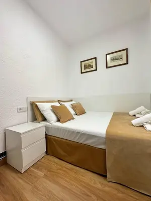 two beds in a room with white walls and wood floors at MI CASA ES TU CASA in Hospitalet de Llobregat
