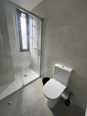 a white bathroom with a shower and a toilet at Hostal La Masia in Manresa