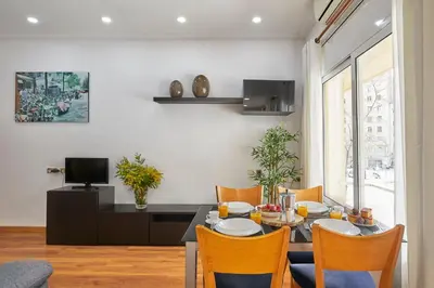 a dining room with a table with chairs and a television at BBarcelona Gràcia Nova Flat in Barcelona