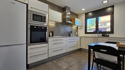 a kitchen with white cabinets and a microwave and a table at Cal Sidru Castellolí in Castellolí