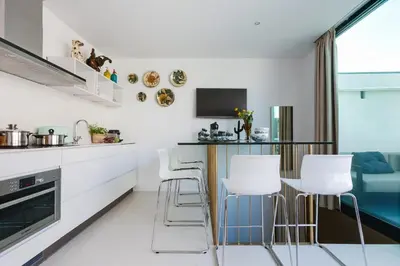 a kitchen with white cabinets and a bar with stools at En Ville Boutique Apartments Sant Antoni in Barcelona