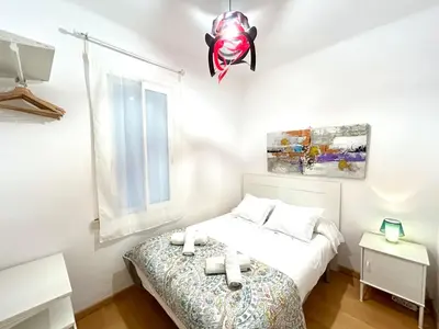 a white bedroom with a bed and a window at Apartment carrer d'Olesa in Barcelona