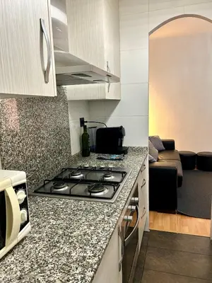 a kitchen with a stove top oven next to a living room at Apartment carrer d'Olesa in Barcelona