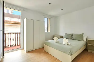 a white bedroom with a bed and a large window at Ma Bright apartment next to Parc de Montjuïc in Barcelona