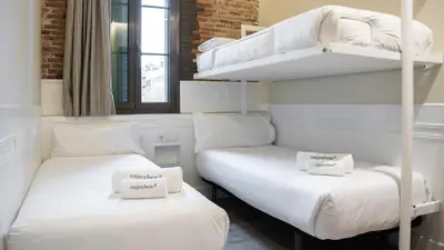 two beds in a room with white bunk beds at Enjoybcn Miro Apartments in Barcelona
