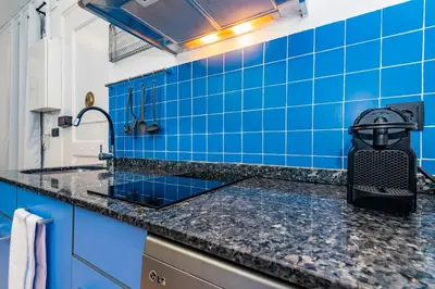 a blue tiled kitchen with a black counter top at R&B Mila in Barcelona