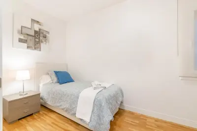 a white bedroom with a bed and a night stand at Elegance Barcelona Rentals in Barcelona