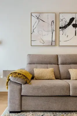 a couch in a living room with two pictures on the wall at Barcelona Amelie Apartment in Hospitalet de Llobregat