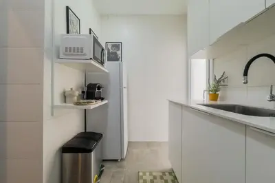 a white kitchen with a sink and a refrigerator at Barcelona Amelie Apartment in Hospitalet de Llobregat