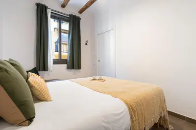 a bedroom with a white bed with a window at Lodging Apartments Almirall Beach 41 in Barcelona