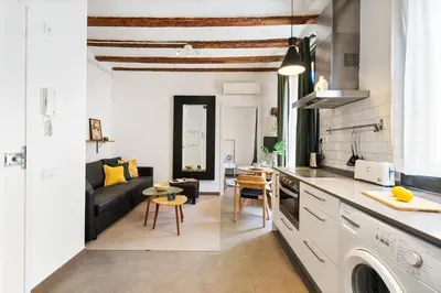 a kitchen and living room with a couch and a table at Lodging Apartments Almirall Beach 41 in Barcelona