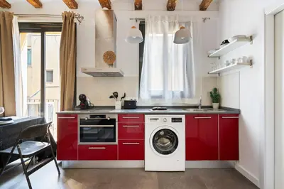 a kitchen with red cabinets and a washing machine at Lodging Apartments Almirall Beach 51 in Barcelona