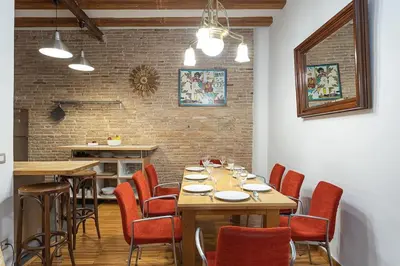 a dining room with wooden tables and red chairs at Canela Homes BARCELONA JOVELLANOS in Barcelona