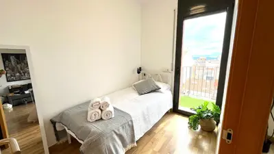 a bedroom with a bed and a large window at APARTAMENTO CON TERRAZA BY PRESTIGI in Terrassa