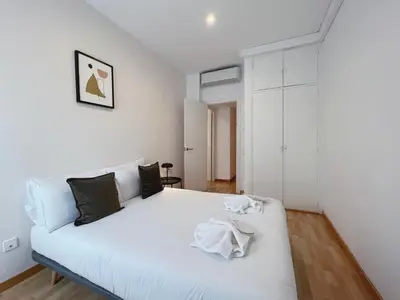 a white bedroom with a white bed with black pillows at Stay U-nique Apartment General Mitre in Barcelona
