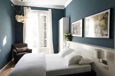 a bedroom with blue walls and a bed and a chair at Close to Passeig de Gracia in Barcelona