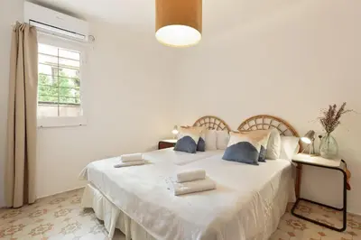 a white bedroom with a large white bed with blue pillows at Sagrada Familia Vl by Enjoy Apartments in Barcelona