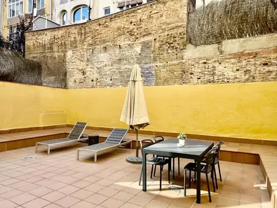 a patio with a table and chairs and an umbrella at Feelathome Mozart Apartments in Barcelona