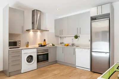 a kitchen with white cabinets and a washer and dryer at Feelathome Mozart Apartments in Barcelona
