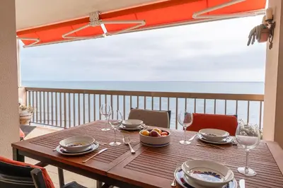 a wooden table with wine glasses and a bowl of fruit at Piso con vista increíble al mar in Sant Andreu de Llavaneres