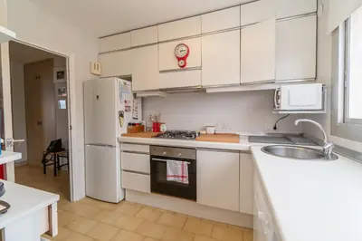 a kitchen with white cabinets and a sink and a refrigerator at Piso con vista increíble al mar in Sant Andreu de Llavaneres