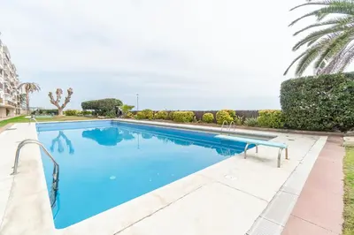 a large swimming pool with blue water at Piso con vista increíble al mar in Sant Andreu de Llavaneres
