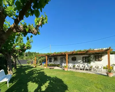 a garden with white chairs and a pergola at VILLA MasÍa CAL TONI in Pineda de Mar