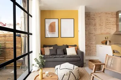 a living room with a gray couch and yellow wall at Lodging Apartments Rambla Poblenou 12 in Barcelona