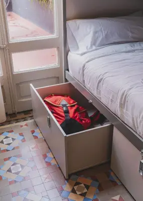 a drawer under a bed with a red backpack at Piulet Hostel in Barcelona