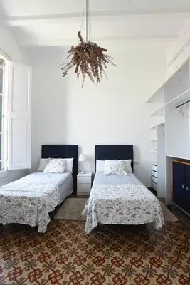 a bedroom with two beds and a chandelier at Vila d'Alba in Sant Andreu de Llavaneres