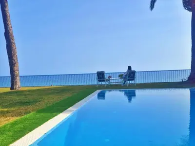 a person sitting on a bench next to a swimming pool at Preciosa casa al borde de un acantilado in Arenys de Mar
