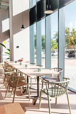 a row of tables and chairs in a room with windows at Atenea Living in Mataró