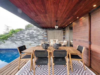 a wooden table and chairs on a deck with a pool at Xauxa in Sant Pere de Vilamajor