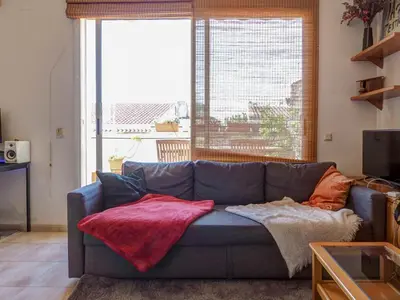 a living room with a blue couch with a red blanket at Castell Apartment by Hello Homes Sitges in Sitges